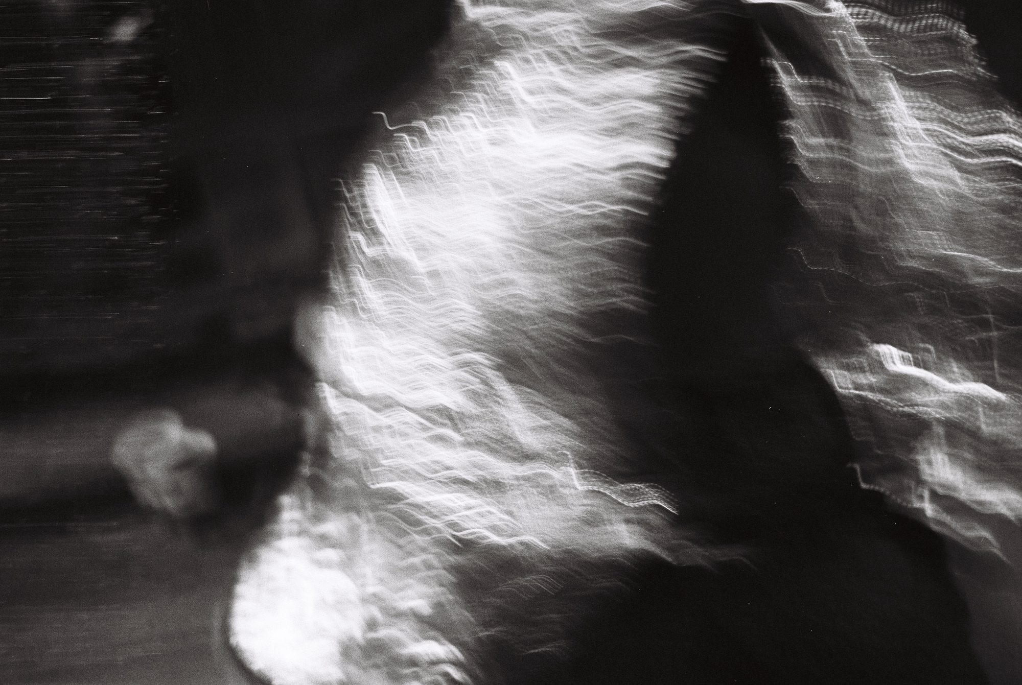 Abstract black and white motion blur, rippling streaks of light across a dark figure