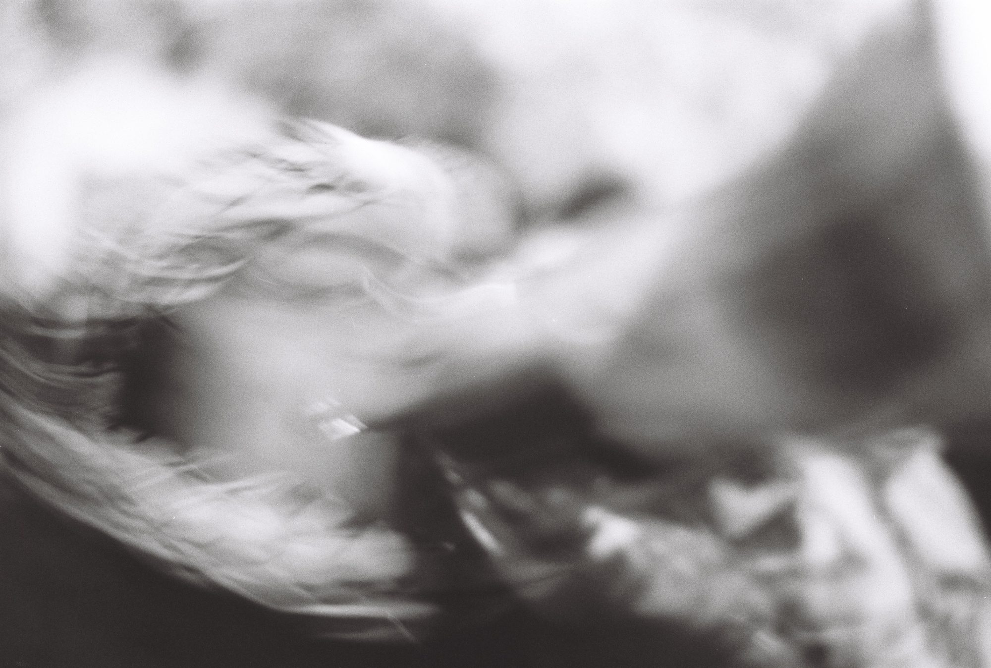 Soft, heavily blurred black and white image of swirling hair and fabric in motion