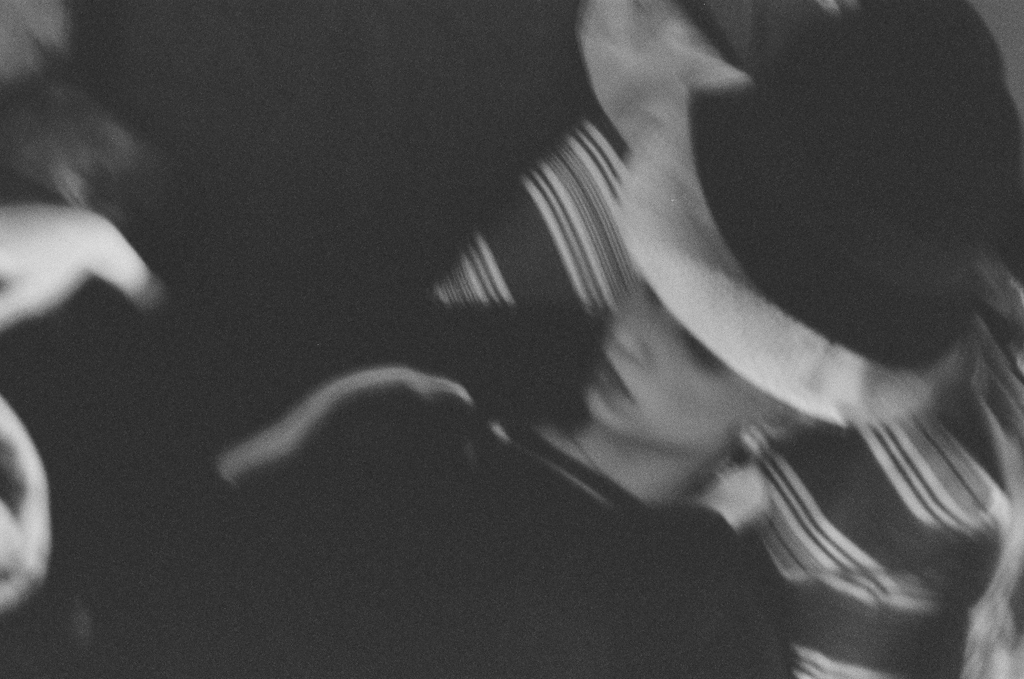 Black and white motion blur of a figure in a wide-brimmed hat and striped light