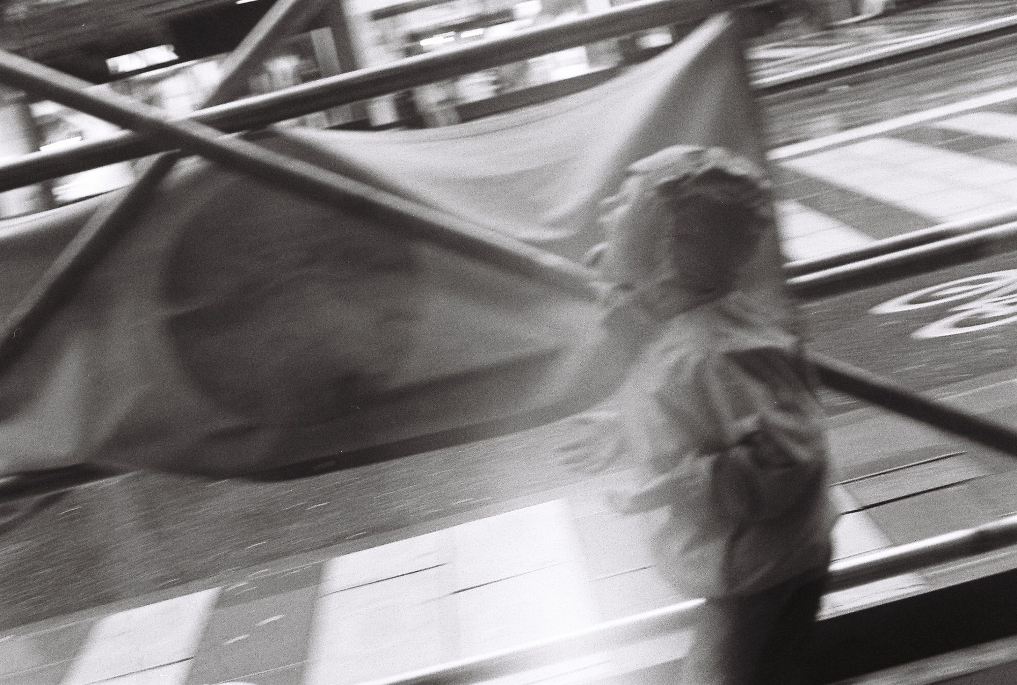 Motion blur of a figure waving a large flag behind crossed metal railings