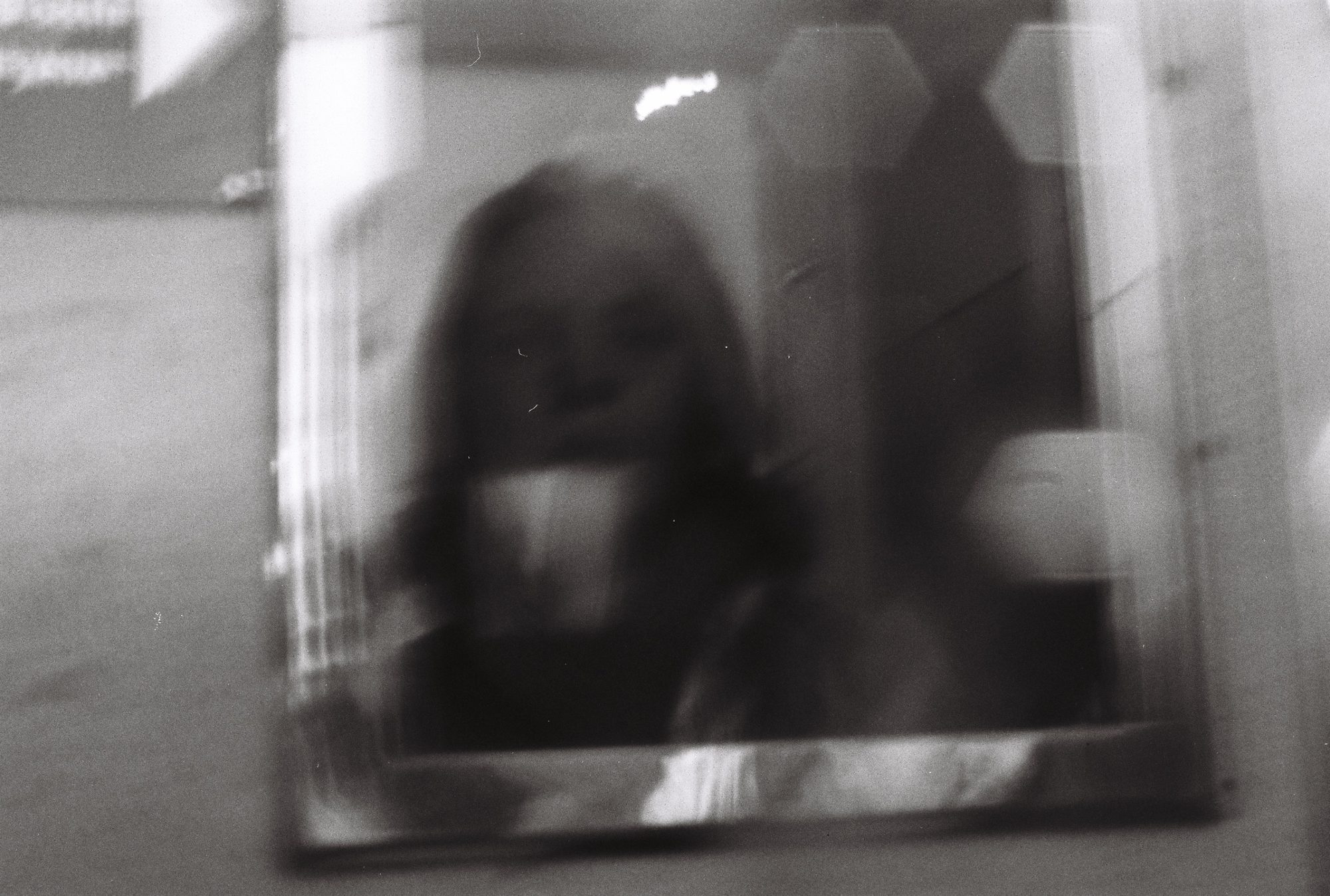 A blurred reflection of a figure in a framed mirror