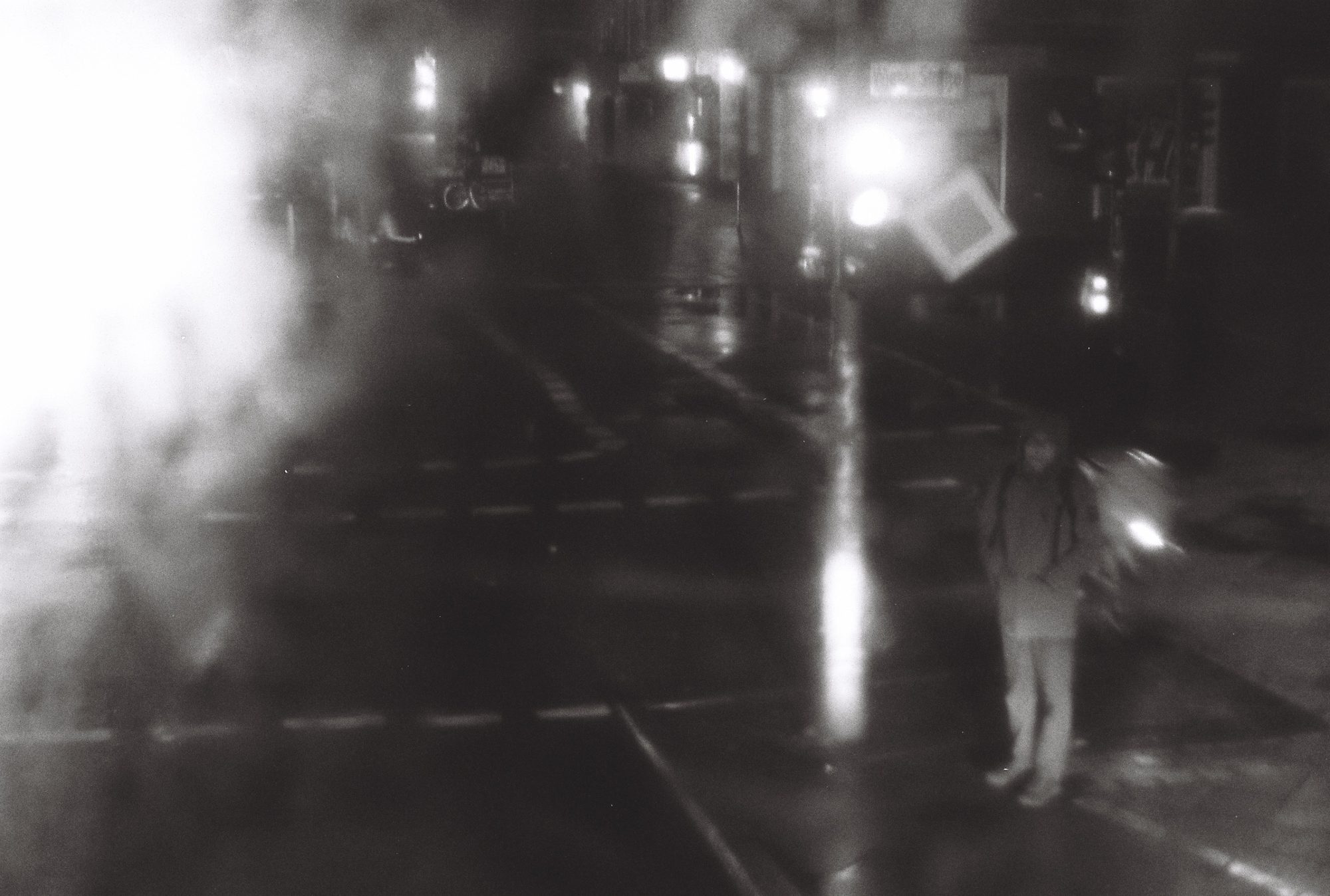 A rainy night street in haze and steam, a lone figure by the tram tracks