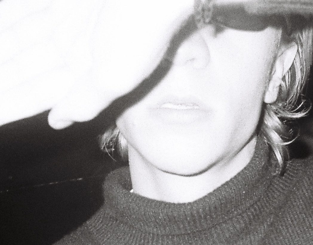 Flash close-up of a face half hidden by a hand and a cap