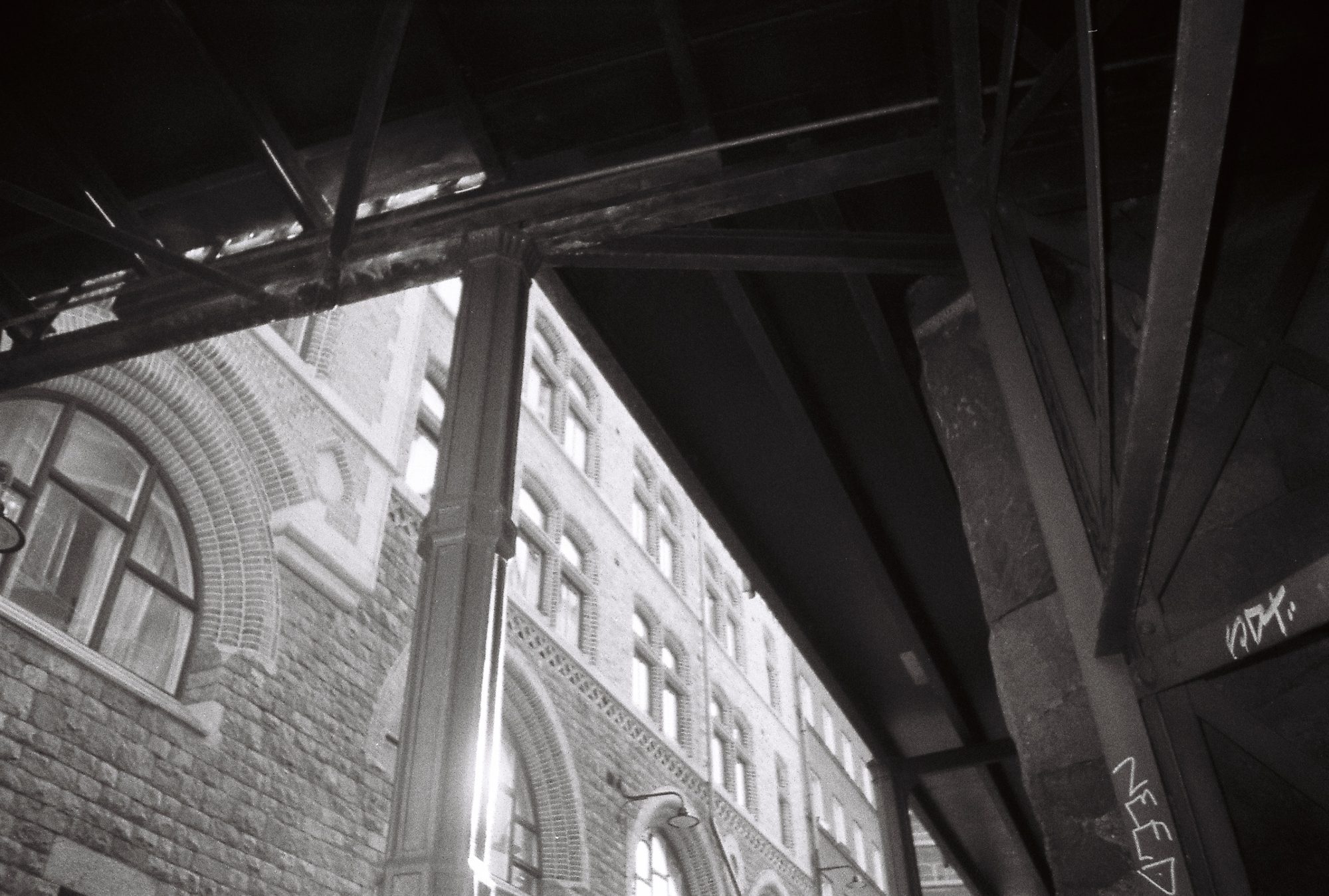 Looking up at a steel railway viaduct beside an ornate brick building