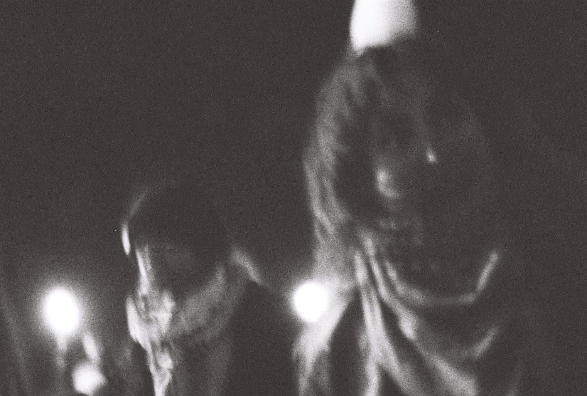 Two blurred figures in scarves at night, lit by soft street lights