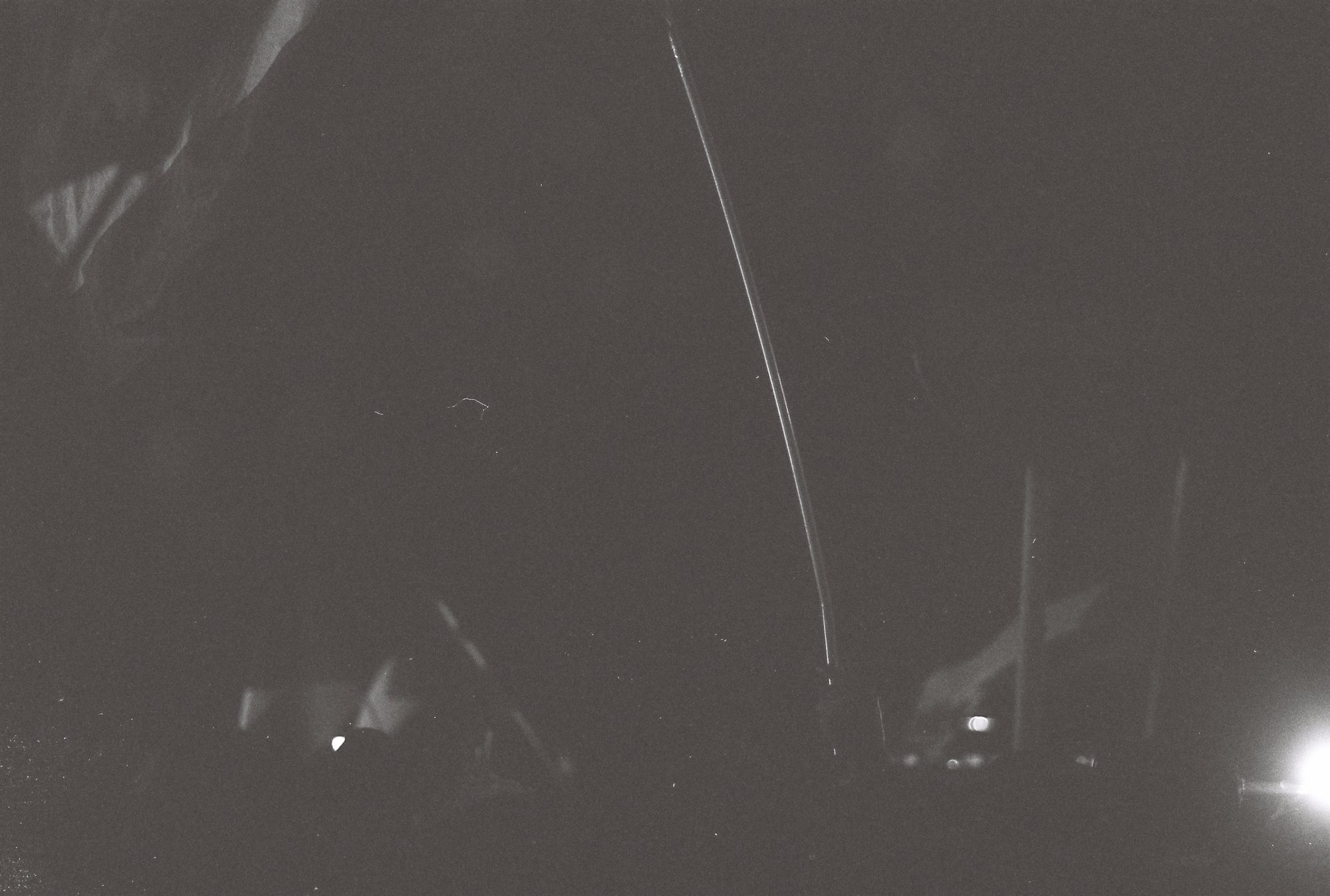 Dark night scene crossed by a thin curved line of light
