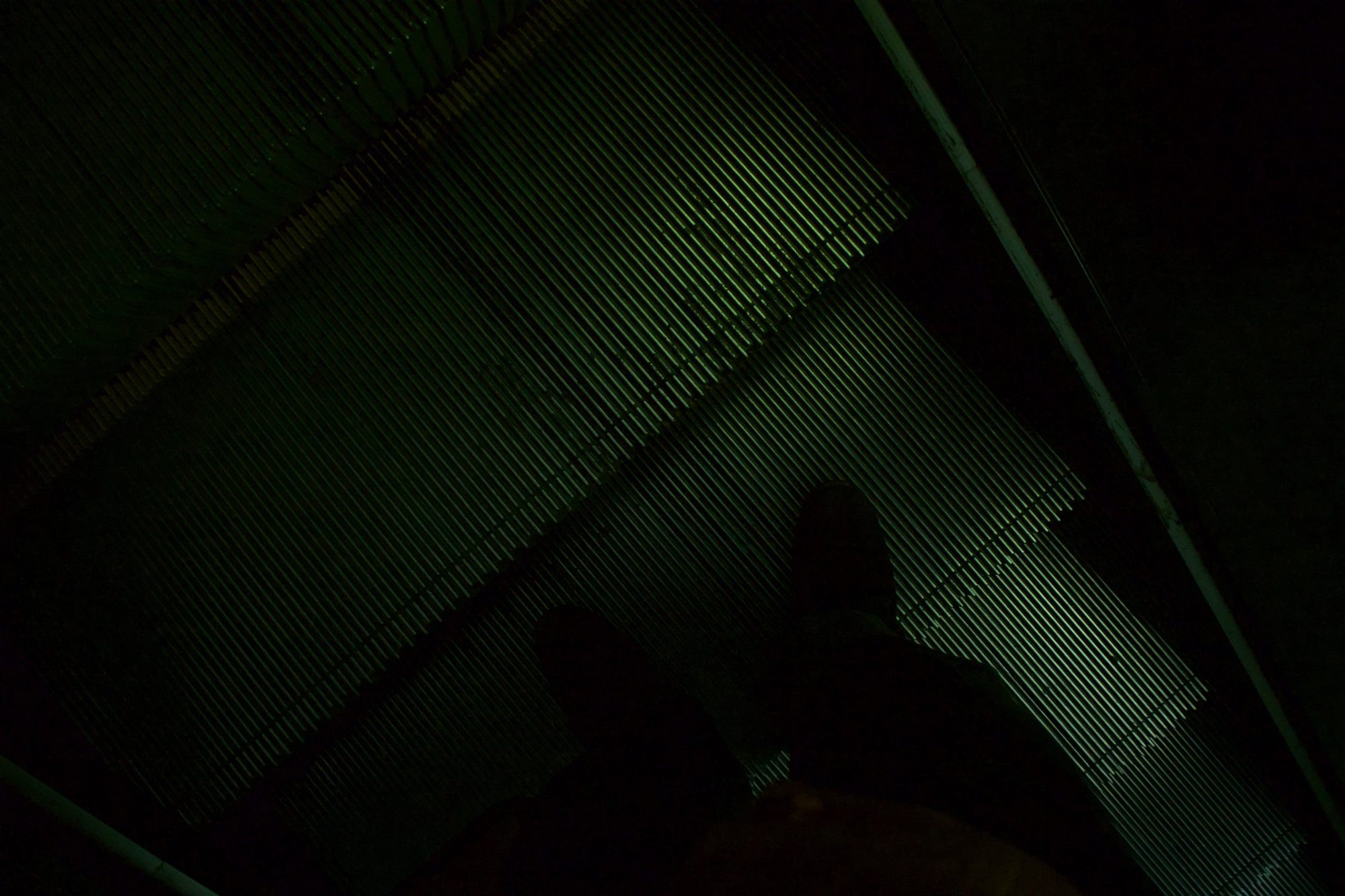 Looking up an escalator in dark green light