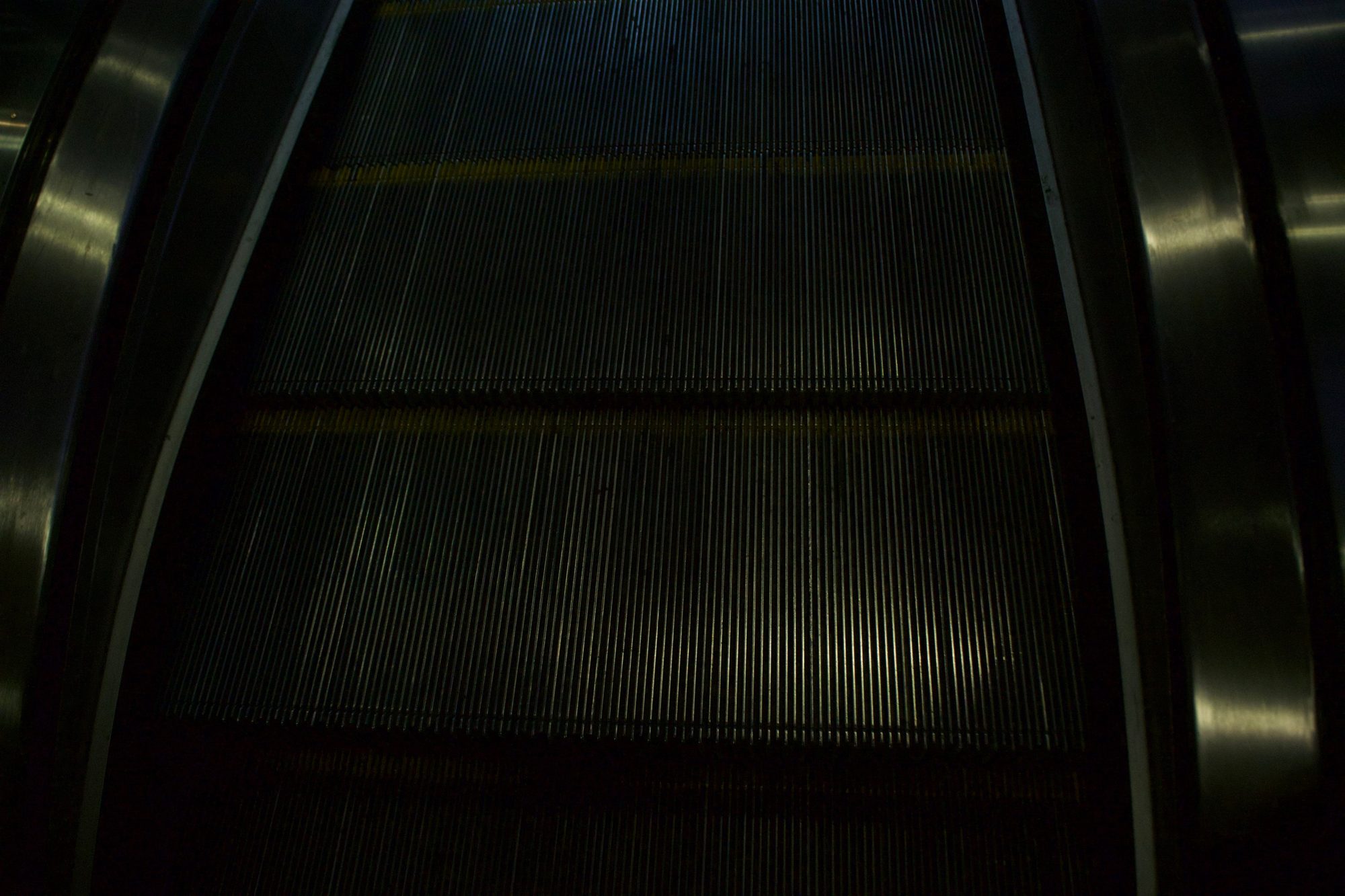 Close view of dark escalator steps with faint yellow edge lines