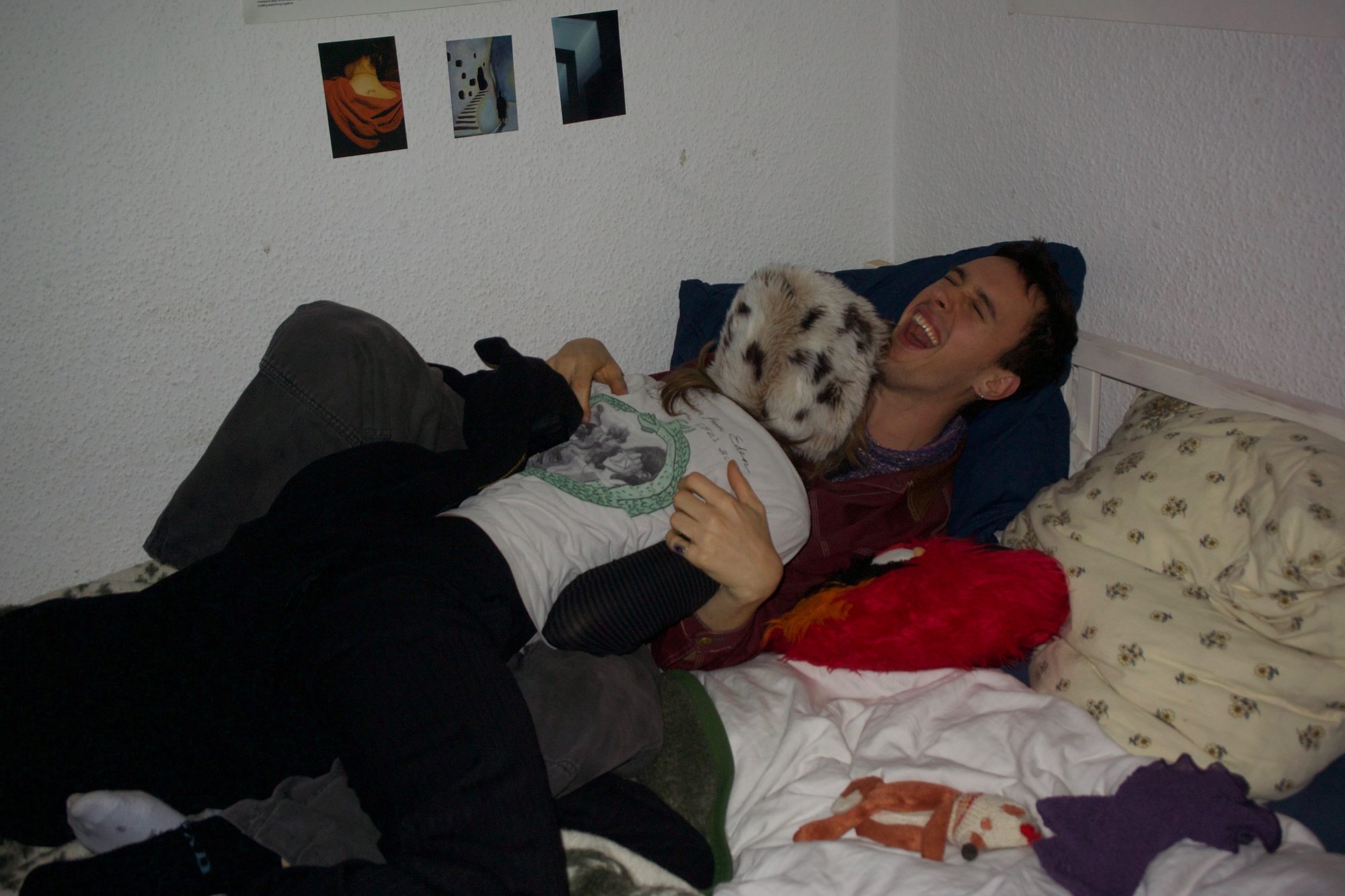 The couple laughing on the bed, his head thrown back as she hugs him